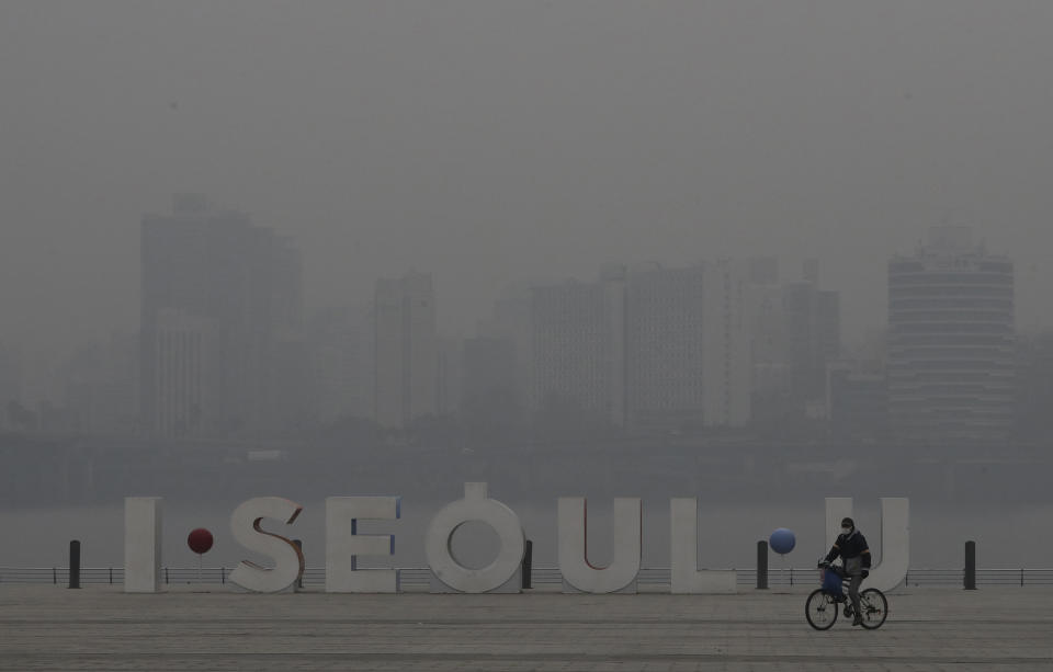 FILE - In this Jan. 14, 2019 file photo, a visitor wearing a mask rides a bicycle along the Han river at a park in Seoul, South Korea. The upcoming Trump-Kim meeting will be a crucial moment for South Korean President Moon Jae-in, who is desperate for more room to continue his engagement with North Korea, which has been limited by tough U.S.-led sanctions against Pyongyang. (AP Photo/Lee Jin-man, File)