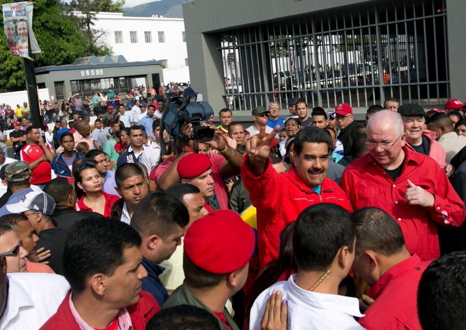 El presidente Nicolás Maduro hace la señal de la victoria al llegar a votar acompañado del embajador venezolano en las Naciones Unidas, Rafael Ramírez, durante los comicios para elegir una nueva Asamblea Nacional. Caracas, domingo 06 de diciembre de 2015. Según las encuestas de intención de voto, la oposición aventaja por 30 puntos al oficialismo. (AP foto/Alejandro Cegarra)