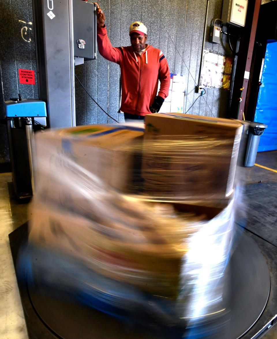A pallet of food items spins as it is wrapped in plastic on a turntable controlled by Nate Mays at the food bank in November.