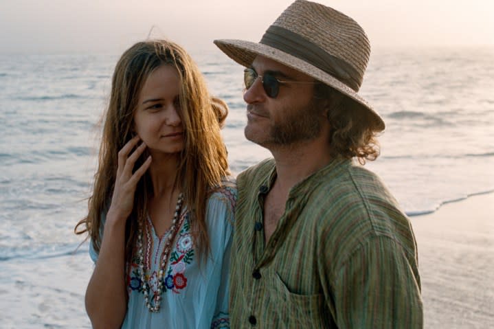 Katherine Waterston and Joaquin Phoenix walk near the ocean together in Inherent Vice.