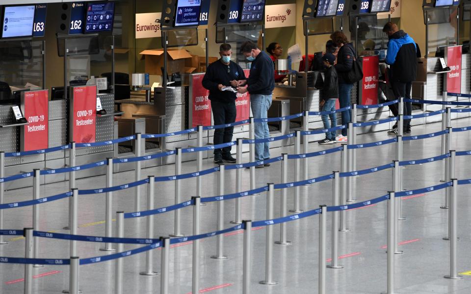 Travellers stand at an information desk about the free of charge coronavirus COVID-19 testing station at Duesseldorf airport on October 19, 2020, amid the novel coronavirus COVID-19 pandemic. (Photo by Ina FASSBENDER / AFP) (Photo by INA FASSBENDER/AFP via Getty Images)