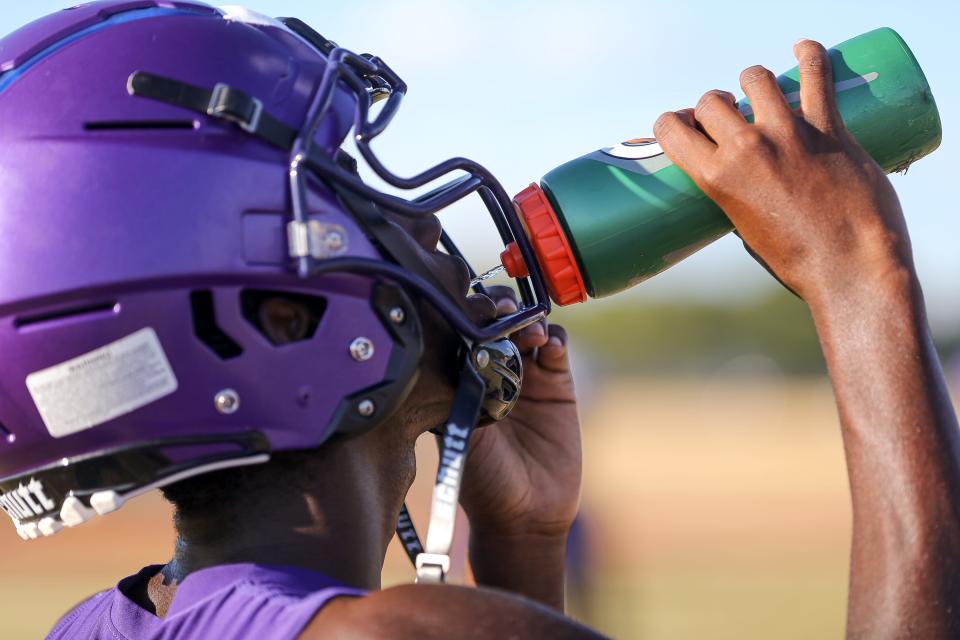 An LBJ football player takes a drink of water during a break in training at a team practice on Aug. 1. Mandatory water breaks for players is one of many steps Austin-area high school coaches have taken this August to combat the heat.