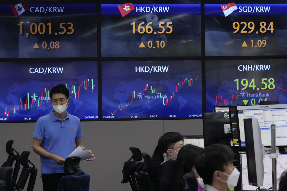 A currency trader walks by the screens showing the foreign exchange rates at the foreign exchange dealing room of the KEB Hana Bank headquarters in Seoul, South Korea, Thursday, July 7, 2022. Asian stock markets gained Thursday after the Federal Reserve said higher U.S. interest rates might be needed to cool inflation.(AP Photo/Ahn Young-joon)