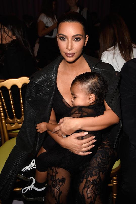 Kim Kardashian West and North West sitting front row at a fashion show wearing sheer lace outfits.