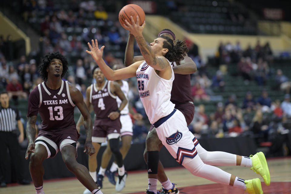 Florida Atlantic forward Tre Carroll (25) shoots while falling after getting fouled by Texas A&M forward Wildens Leveque, right, as forward Solomon Washington (13) watches during the first half of an NCAA college basketball game, Friday, Nov. 24, 2023, in Kissimmee, Fla. (AP Photo/Phelan M. Ebenhack)