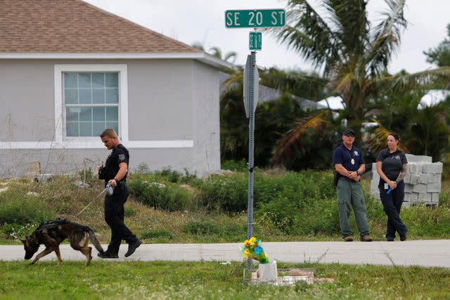 <p>Ricardo Rolon / USA Today Network</p> A Lee County Sheriff K-9 deputy surveys the crime scene, March 18.