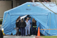 Workers exit a large tent set up in front of the emergency room at EvergreenHealth Medical Center, Tuesday, March 17, 2020, in Kirkland, Wash., near Seattle. In the area that has led the country in COVID-19 coronavirus cases and also across the country, hospitals are gearing up for an onslaught of coronavirus patients, but staff on the front lines are stretched thin and don't have the equipment they need to protect themselves from the highly contagious virus. (AP Photo/Ted S. Warren)