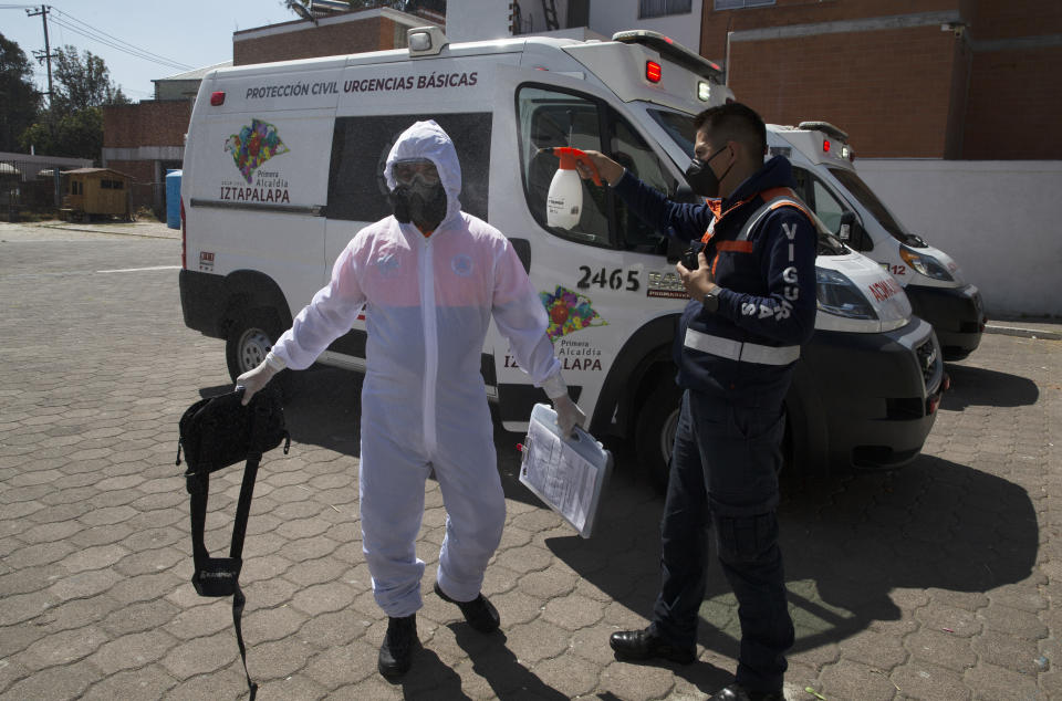 Paramedic Eduardo Vigueras, head of the morning shift, right, disinfects his partner Oscar Reyes after moving a COVID-19 patient to a hospital in the Iztapalapa district of Mexico City, Tuesday, Feb. 2, 2021. (AP Photo/Marco Ugarte)
