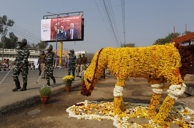 Security officers patrol on a street decorated with floral arrangements in Agra