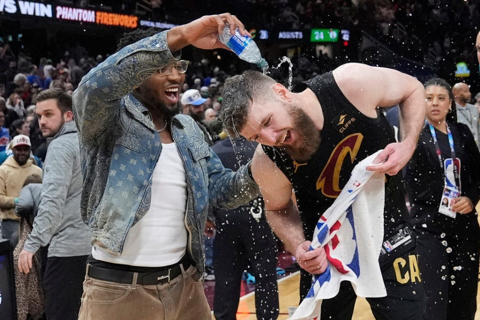 Injured Cleveland Cavaliers guard Donovan Mitchell, left, douses teammate Dean Wade, right, with water after the Cavaliers defeated the Boston Celtics in an NBA basketball game, Tuesday, March 5, 2024, in Cleveland. (AP Photo/Sue Ogrocki)