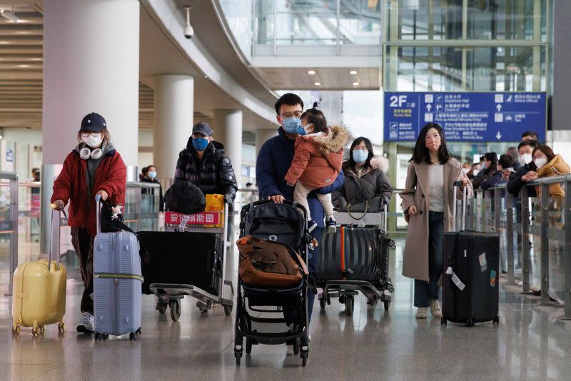 Passengers push their luggage through the international arrivals hall at Beijing Capital International Airport after China lifted the COVID-19 quarantine requirement for inbound travellers in Beijing