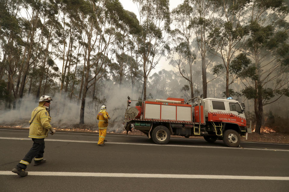 A firefighting crew battles a fire near Burrill Lake, Australia, Sunday, Jan. 5, 2020. Milder temperatures Sunday brought hope of a respite from wildfires that have ravaged three Australian states, destroying almost 2,000 homes. (AP Photo/Rick Rycroft)