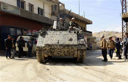 Residents watch Lebanese army soldiers on their armoured vehicle entering the Sunni Muslim border town of Arsal, in eastern Bekaa Valley March 19, 2014. REUTERS/Hassan Abdallah