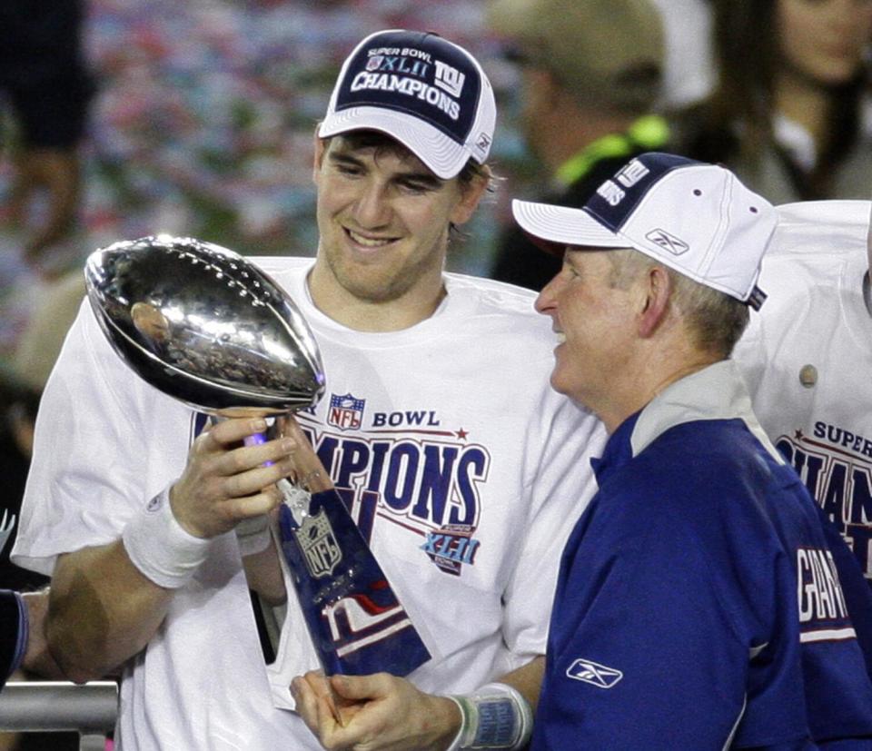 Giants quarterback Eli Manning and coach Tom Coughlin inspect the Vince Lombardi Trophy after winning Super Bowl XLII.