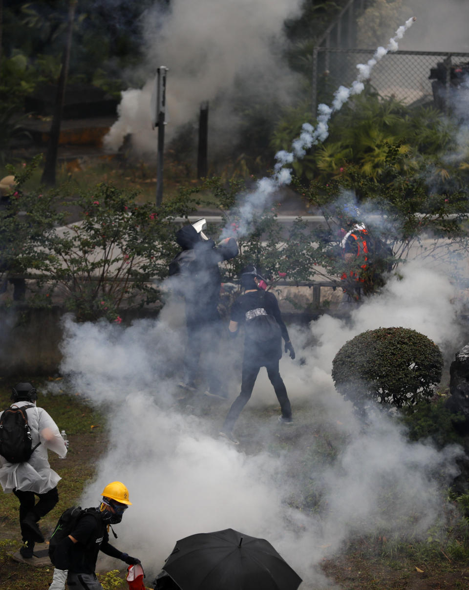 Protesters throw back tear gas at police in Hong Kong, Sunday, Oct. 6, 2019. Shouting "Wearing mask is not a crime," tens of thousands of protesters braved the rain Sunday to march in central Hong Kong as a court rejected a second legal attempt to block a mask ban aimed at quashing violence during four months of pro-democracy rallies. (AP Photo/Vincent Thian)