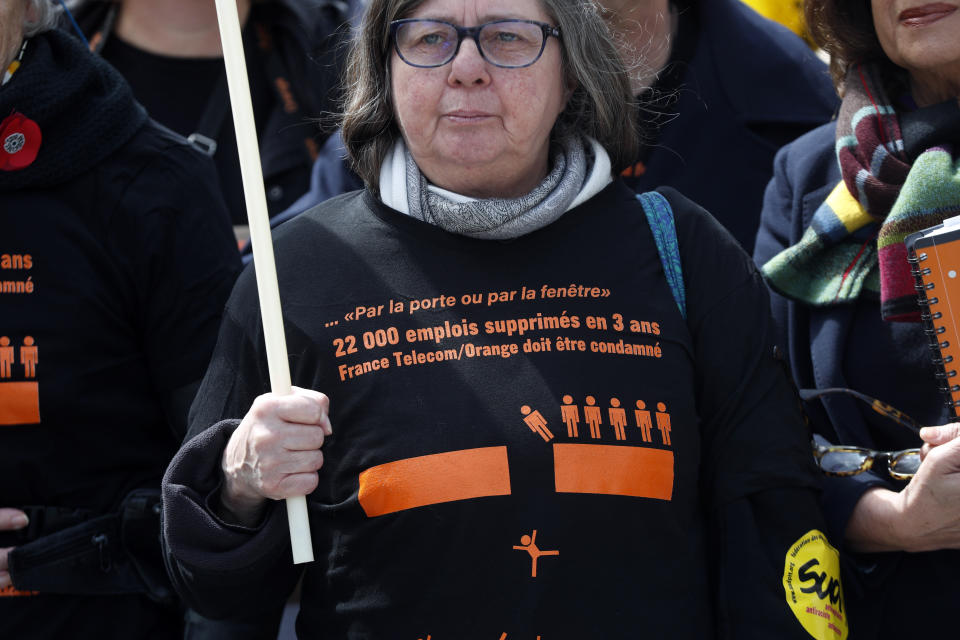 A French unions member wears a shirt reading " 22,000 jobs cut in 3 years. France Telecom must be condemned" at the start of the trial of French group France Telecom, in front of the Paris' courthouse, on Monday, May 6, 2019. French telecom giant Orange and seven former or current managers are going on trial accused of moral harassment over a wave of employee suicides a decade ago. (AP Photo/Thibault Camus)