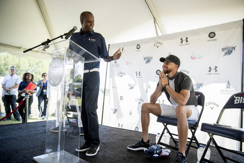 Howard University president Wayne Frederick, left, looks at Golden State Warriors guard Stephen Curry during a news conference at Langston Golf Course in Washington, Monday, Aug. 19, 2019, where Curry announced that he would be sponsoring men's and women's golf teams at Howard University. (AP Photo/Andrew Harnik)
