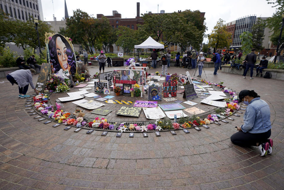 A women kneels in front of a makeshift memorial in honor of Breonna Taylor, at Jefferson Square Park, Thursday, Sept. 24, 2020, in Louisville, Ky. A grand jury on Wednesday, Sept. 23 indicted one officer on counts of wanton endangerment for firing into a home next to Taylor's with people in it, while declining to charge police officers for the fatal shooting of Taylor. (AP Photo/Darron Cummings)