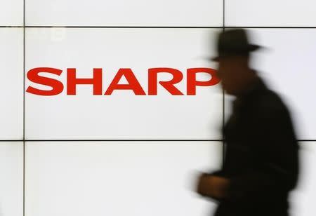 A pedestrian walks past a logo of Sharp Corp at a train station in Tokyo February 3, 2014. REUTERS/Yuya Shino/Files