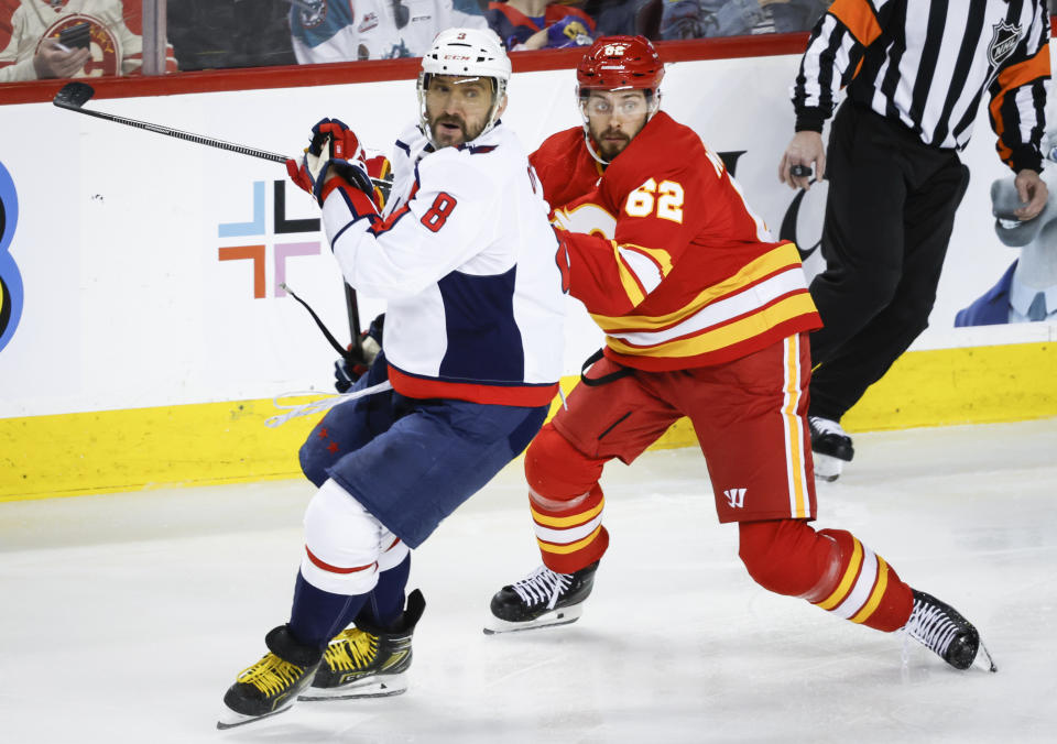 Washington Capitals forward Alex Ovechkin (8) checks Calgary Flames defenseman Daniil Miromanov (62) during first-period NHL hockey game action in Calgary, Alberta, Monday, March 18, 2024. (Jeff McIntosh/The Canadian Press via AP)