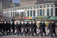 Policemen wear face masks as they march in formation outside the Beijing Railway Station in Beijing, Saturday, Feb. 15, 2020. People returning to Beijing will now have to isolate themselves either at home or in a concentrated area for medical observation, said a notice from the Chinese capital's prevention and control work group published by state media late Friday. (AP Photo/Mark Schiefelbein)