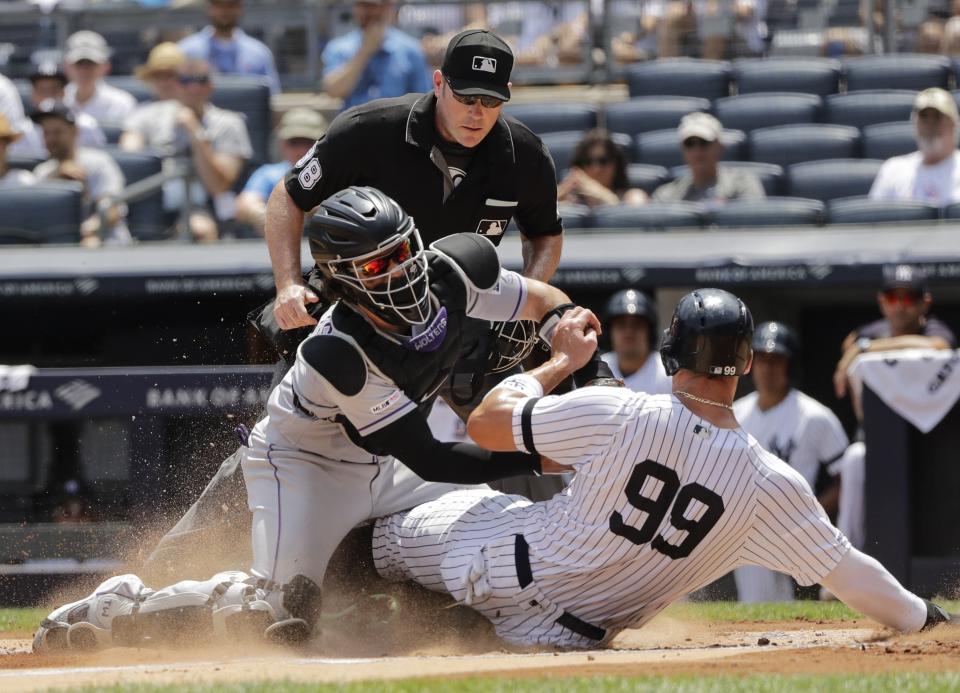 Colorado Rockies catcher Tony Wolters, left, tags out New York Yankees' Aaron Judge, right, during the first inning of a baseball game as home plate umpire Chris Conroy watches Saturday, July 20, 2019, in New York. (AP Photo/Frank Franklin II)