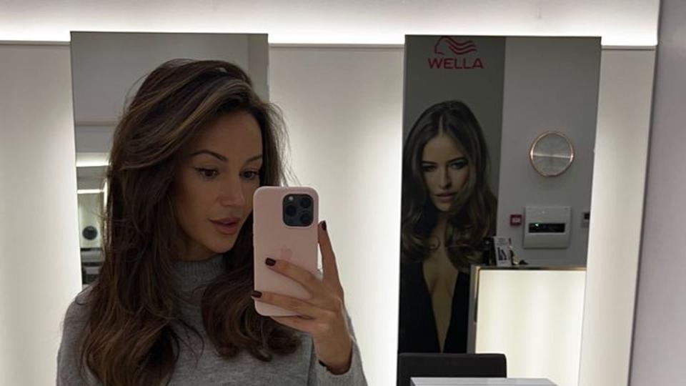 woman posing for mirror selfie in jeans and jumper