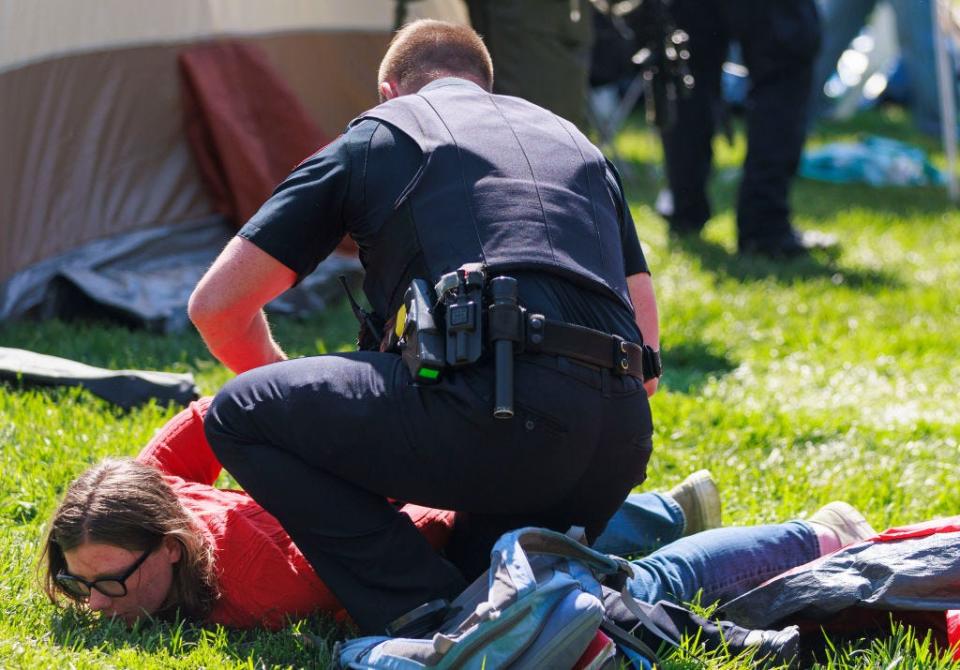 A person is held to the ground by a police officer