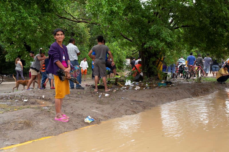 Residents stand on the side of a road flooded by the Chamelecon river after the passing of Storm Iota, in La Lima