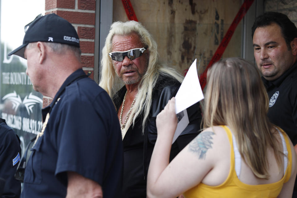 Duane "Dog the Bounty Hunter" Chapman, back, charts with his daughter, Bonnie Jo, outside his storefront that was burglarized before a news conference Friday, Aug. 2, 2019, in Edgewater, Colo. Police in Colorado said Friday they are investigating a reported burglary of a business owned by "Dog the Bounty Hunter" reality TV star Duane "Dog" Chapman. (AP Photo/David Zalubowski)