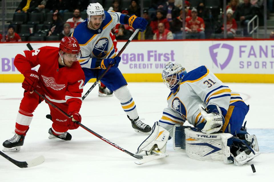 Buffalo Sabres goaltender Dustin Tokarski (31) deflects a shot by Detroit Red Wings center Pius Suter (24) with Sabres defenseman Colin Miller (33) helping defend the goal during the first period Saturday, Nov. 27, 2021, in Detroit.