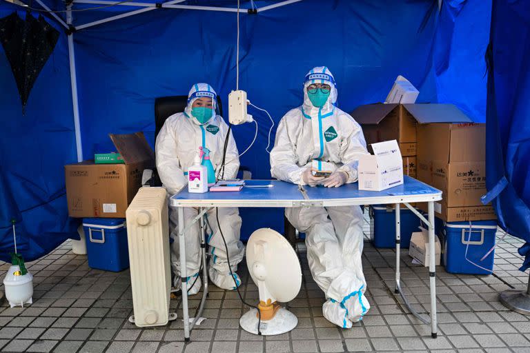 Trabajadores sanitarios esperan a que la gente escanee un código sanitario para realizar la prueba del coronavirus Covid-19 en el distrito de Jing'an, en Shanghái, el 22 de diciembre de 2022.