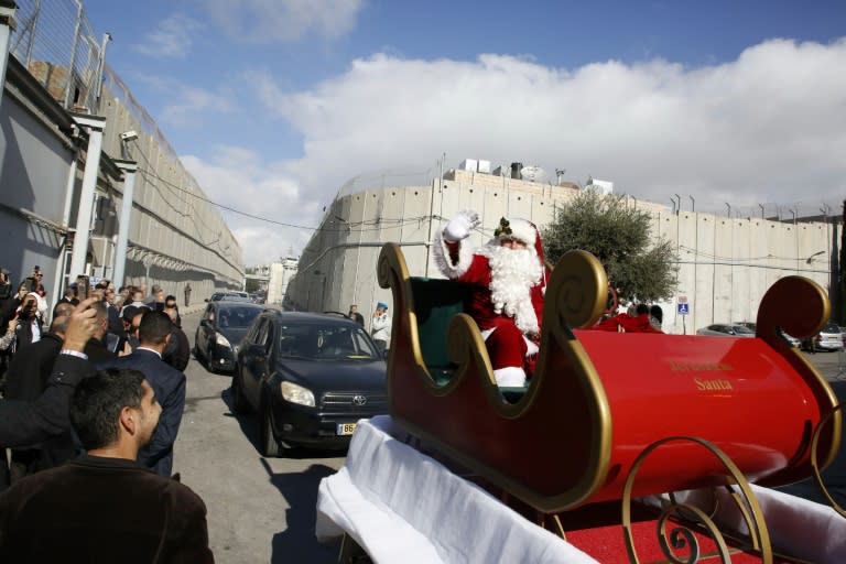 A Santa Claus passing near the controversial Israeli separation barrier, as he arrives in the West Bank city of Bethlehem