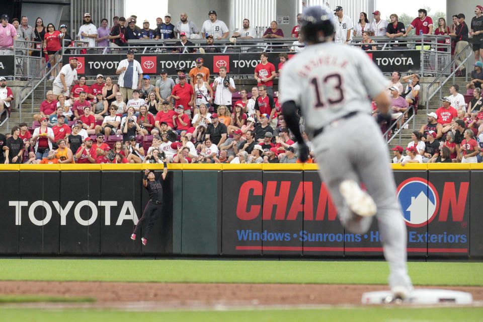 Cincinnati Reds outfielder Stuart Fairchild, back left, leaps at the wall to catch a ball hit by Detroit Tigers' Gio Urshela (13) in the second inning of a baseball game in Cincinnati, Friday, July 5, 2024. (AP Photo/Jeff Dean)