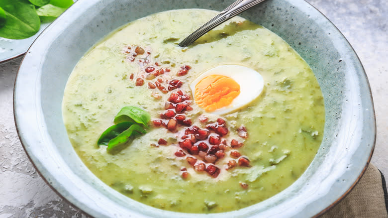 bowl of green soup with bacon topping