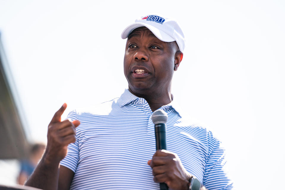 Sen. Tim Scott holds a microphone.