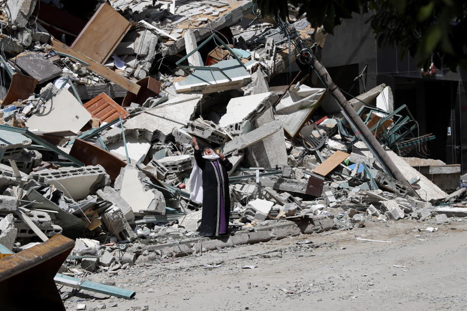 A woman reacts while standing on the rubble of a building that was destroyed by an Israeli airstrike on Saturday that housed The Associated Press, broadcaster Al-Jazeera and other media outlets, in Gaza City, Sunday, May 16, 2021. (AP Photo/Adel Hana)