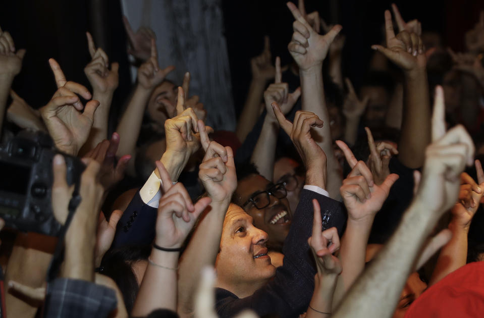 Brazil's presidential candidate for the Workers Party Fernando Haddad is surrounded by students signing a "L" in tribute to former jailed President Luiz Inacio Lula da Silva, during a meeting, in Sao Paulo, Brazil, Wednesday, Sept. 12, 2018. Haddad met with university students who benefited from an affirmative action program for underprivileged youth and racial minorities, put in place during the presidency of Luiz Inacio Lula da Silva. Brazil will hold general elections on Oct. 7. (AP Photo/Andre Penner)