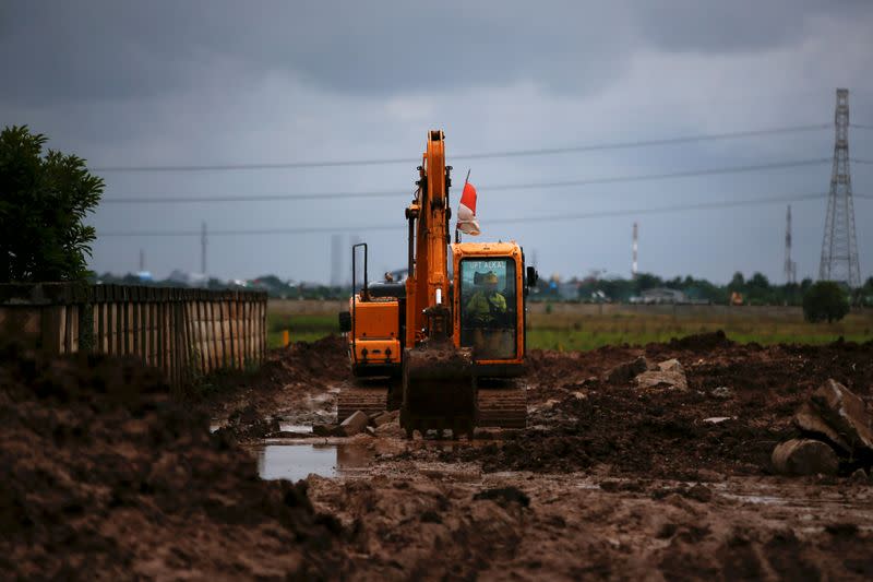 Man rides a heavy vehicle as he works for opening a new cemetery area for the COVID-19 victims in Jakarta