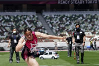 Officials, wearing face masks, look at a shot put by a Japanese competitor during an athletics test event for the Tokyo 2020 Olympics Games at National Stadium in Tokyo, Sunday, May 9, 2021. (AP Photo/Shuji Kajiyama)