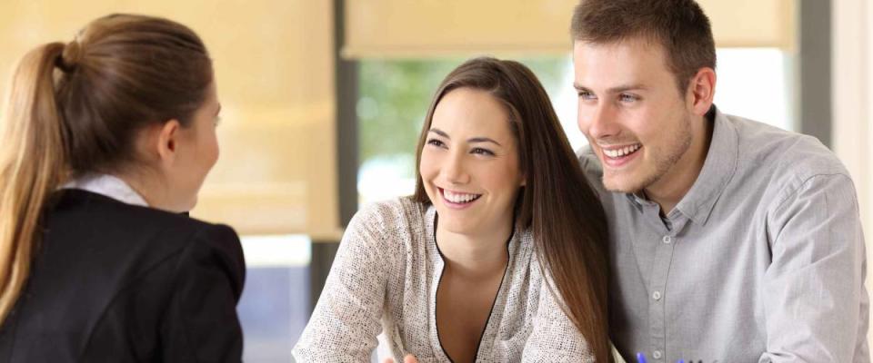 Happy couple talking with a real estate agent at office