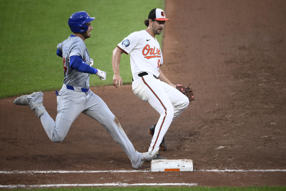 Chicago Cubs' Cody Bellinger, left, is out at first base as Baltimore Orioles starting pitcher Dean Kremer touches first during the fourth inning of a baseball game Tuesday, July 9, 2024, in Baltimore. (AP Photo/Nick Wass)