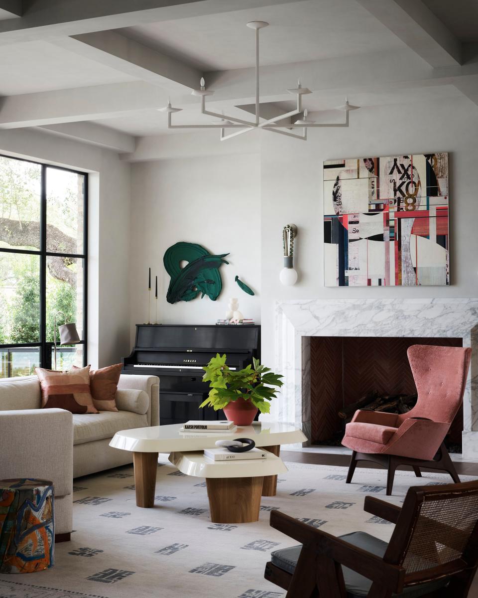 “The living room is the first thing you see. It has gorgeous views of Lake Austin, [so] I wanted it to feel very fresh,” says Seiders. “The coral chair is an homage to [the wife] and her bright personality.” A Craft Associates wingback chair in rosy velvet was paired with two shapely Pierre Agustin Rose coffee tables with oak legs and lacquered tops. The artwork over the fireplace is by Woody Patterson; the one over the piano is by Donald Martiny.