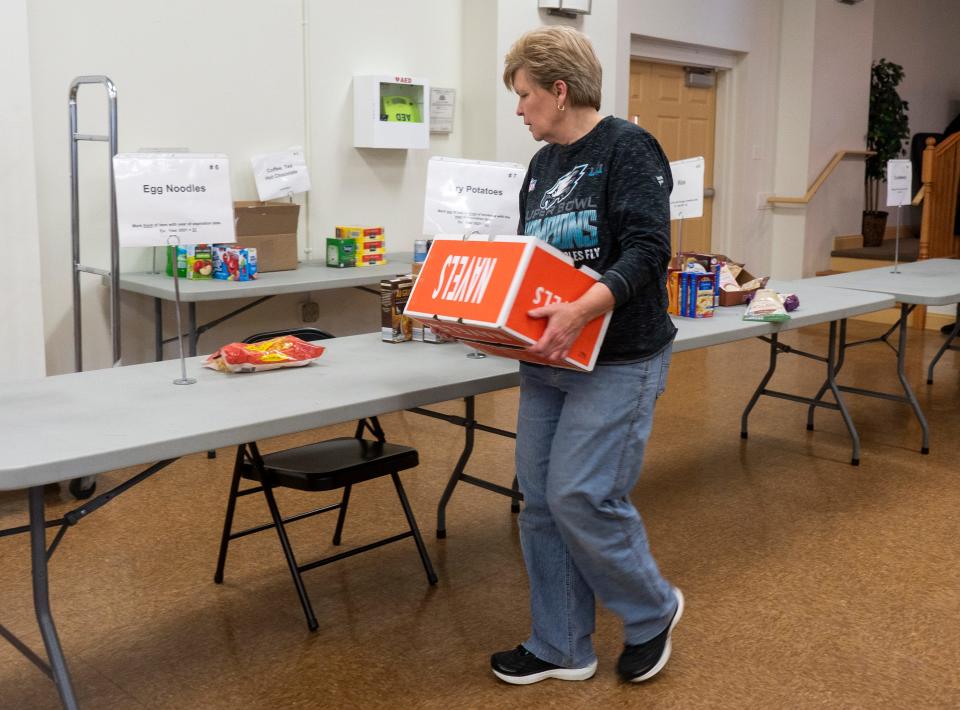 Carrie Muench, from Warminster, takes a box of canned goods to the section of table they belong in at the Warminster food bank in Warminster on Monday, Nov. 20, 2023.

[Daniella Heminghaus | Bucks County Courier Times]
