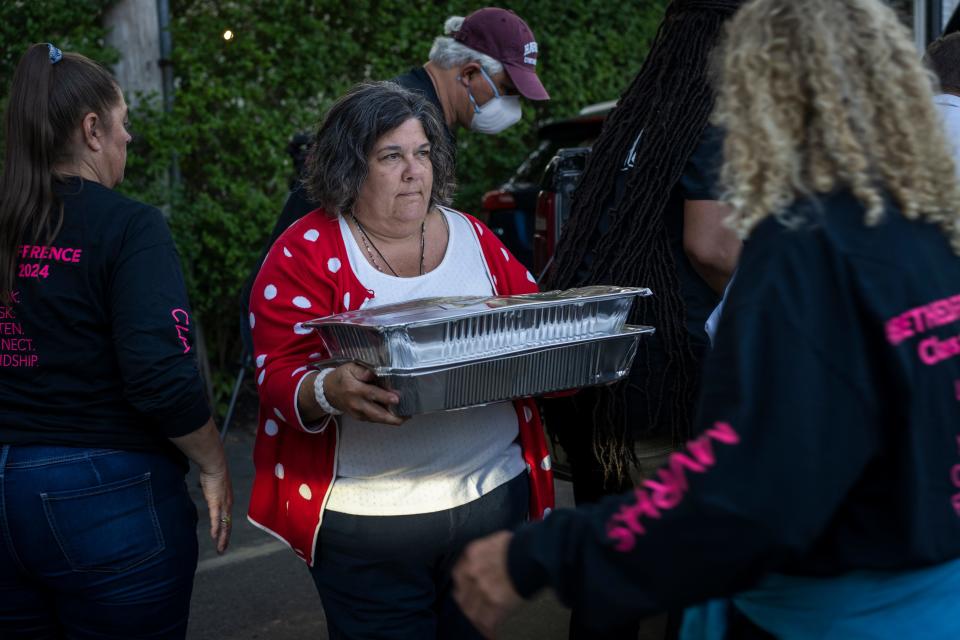 A woman is seen carrying a tinfoil tray through a crowd of people.