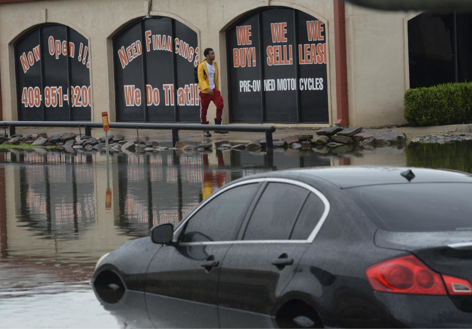 A man walks by one of several cars that were flooded along Interstate 10 in Beaumont, Texas Thursday, Sept. 19, 2019 due to Tropical Storm Imelda. (Guiseppe Barranco/The Beaumont Enterprise via AP)