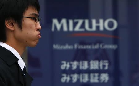 A man walks past a Mizuho Financial Group bank branch in Tokyo January 30, 2014. REUTERS/Yuya Shino/Files