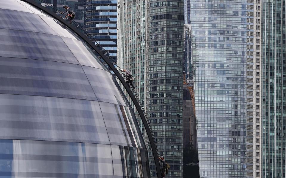 Workers climb down the dome of the Apple store in Singapore - Getty