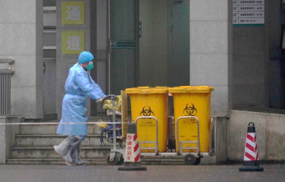 Staff move bio-waste containers past the entrance of the Wuhan Medical Treatment Center, where some infected with a new virus are being treated. (Photo: ASSOCIATED PRESS)