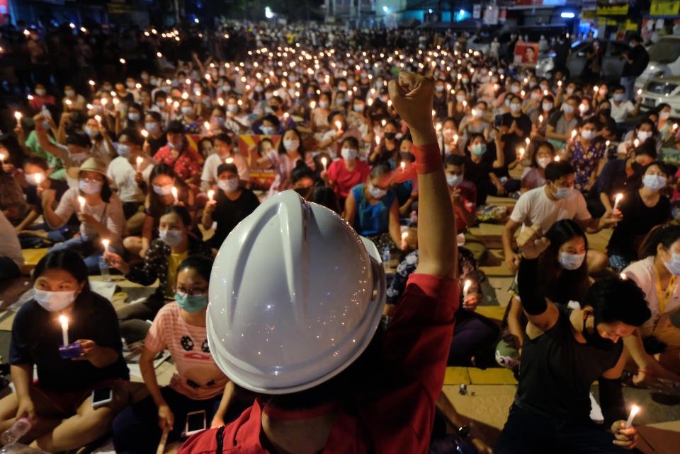An anti-coup protester raises his hand with clenched fist in front of a crowd during a candlelight night rally in Yangon, Myanmar Sunday, March 14, 2021. At least four people were shot dead during protests in Myanmar on Sunday, as security forces continued their violent crackdown against dissent following last month's military coup. (AP Photo)